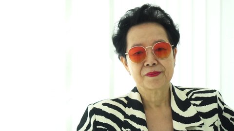Confident Asian elderly woman with stylish fashion dress colourful sunglasses and zebra pattern dress