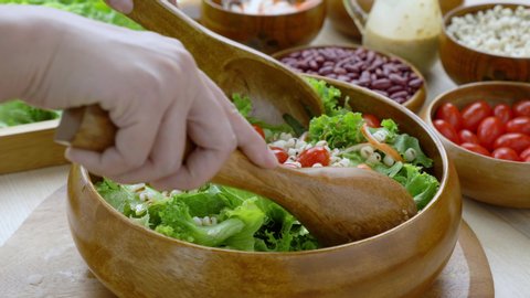 Hand woman chef Mixing Green Salad , Millet,Crab Stick In glass bowl. Breakfast fresh salad and clean vegetable can eat raw. Nutritious and enzymes in Salad mix leaves green vegetable can detox. 