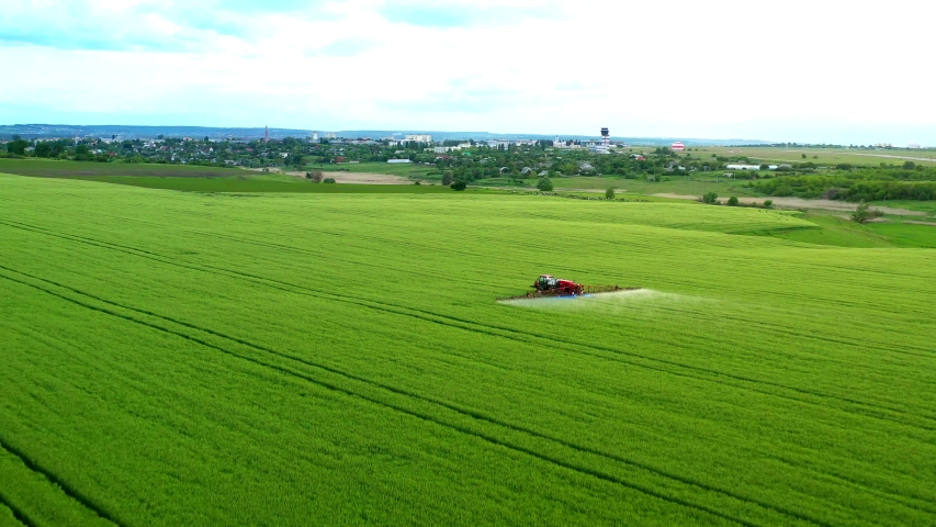 Aerial view of a tractor that irrigates the field with a young, fresh potato at sunset. The process of spraying field growths from insects and loaders.DJI Mavic 2 Pro Royalty-Free Stock Footage #1053740462