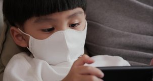 Little boy playing mobile at home. Eyes of boy in protective mask closeup. He spending time during COVID-19 quarantine.