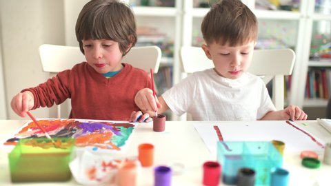 Cute funny kids doing their craft, painting at kindergarten