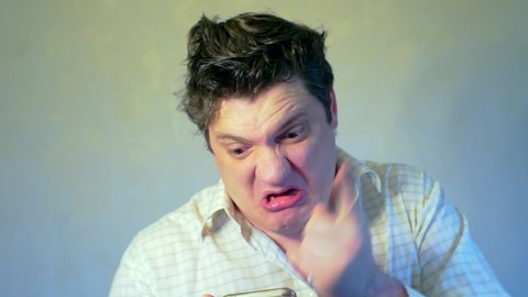 Funny angry swearing man with tousled hair who is holding a smartphone. humorous portrait of a displeased emotional boss