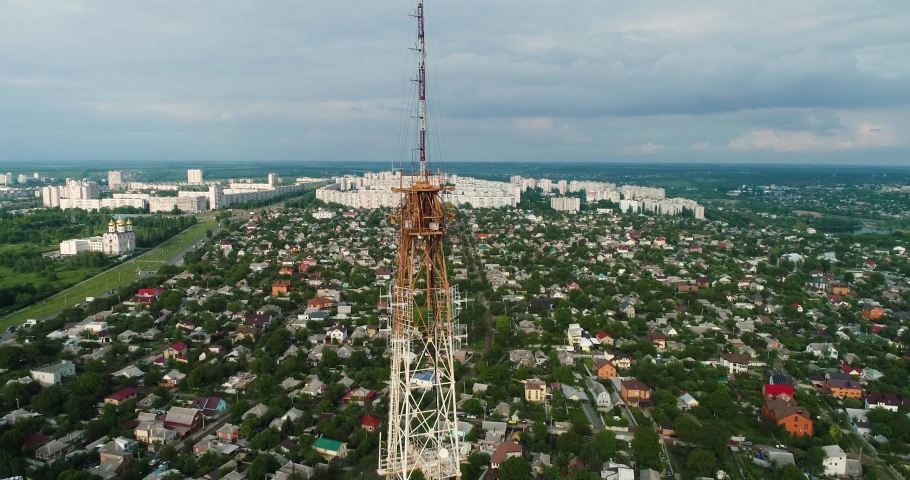 Closeup aerial shot around of tall telecommunication tower in city. Telecom tower antennas and satellite transmits the signals of cellular 5g 4g mobile signals to the consumers and smartphones.