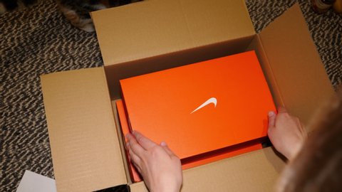 Paris, France - Circa 2020: Cute cat helping woman to unbox unpack new Nike Sport Running Shoes parcel with professional running shoes