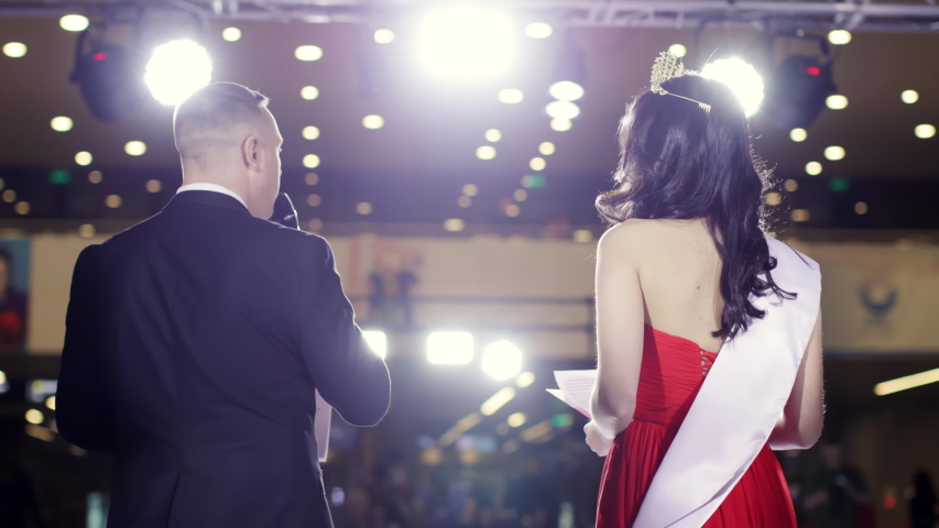 Beauty leading fashion show speak stage closeup speech attractive people catwalk defile 4K. Handsome man and cute girl stand back view scene modern vogue. Two model speaker standing spotlight podium.