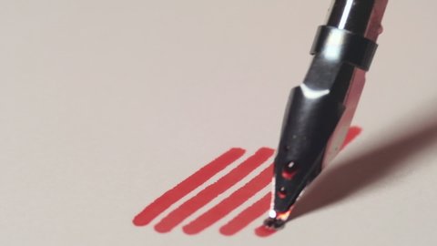Close up of dip pen drawing thick lines by red ink. 4K resolution macro shot. High quality audio recorded with condenser microphone.