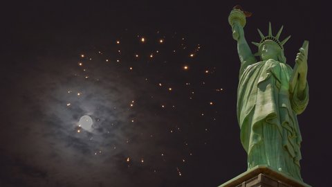 Independence Day patriotic US Holiday with fourth of july Statue of Liberty on fireworks exploding in mysterious night sky with over night full moon