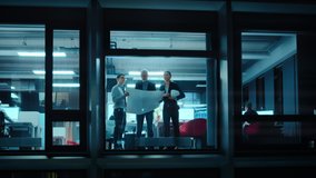Footage from Outside the Window: Architects and Engineers with Hard Hats Stand Next to a Window in Office and Look at Blueprints on Paper. Senior Specialists Explains the Job to His Apprentice. - Powered by Shutterstock - Get 15% off with code: PIKWIZARD15