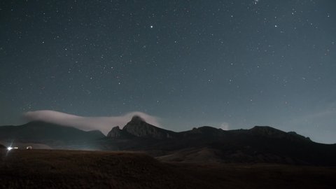 the footing of the timelapse of the night starry sky moves over the mountain range on which goes the white mist