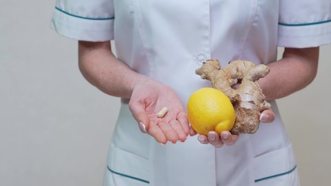 nutritionist doctor healthy lifestyle concept - holding ginger root, lemon and vitamin pill