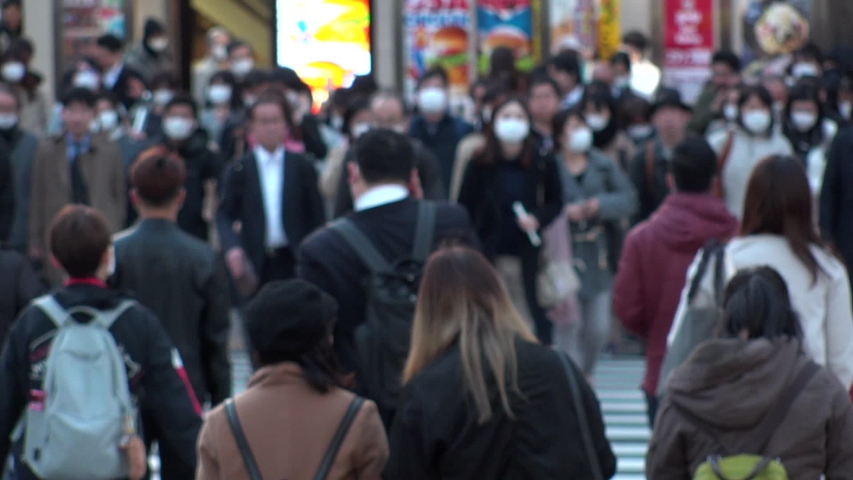 TOKYO, JAPAN - MAR 2020 : Crowd of people at the street near Shinjuku station in evening rush hour. Commuters and tourists wearing surgical mask to protect from Coronavirus (COVID-19). Slow motion. Royalty-Free Stock Footage #1053782216