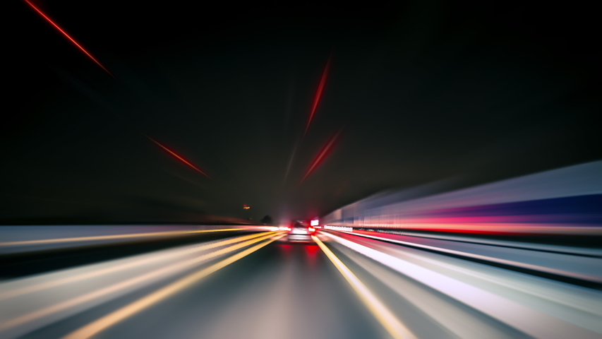 Driving fast on the German Autobahn and through a town at night, dynamic time lapse video with motion blur  Royalty-Free Stock Footage #1053784343