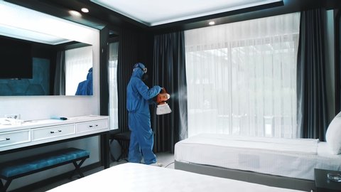 Man in blue protective suit in the hotel sprays hotel rooms to prevent the contamination of corona virus