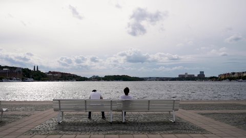 People sitting on a bench in front of water body 