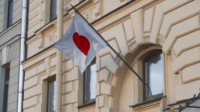 The Japanese flag is developing against the background of an old yellow architectural building. Consulate of Japan in Russia.