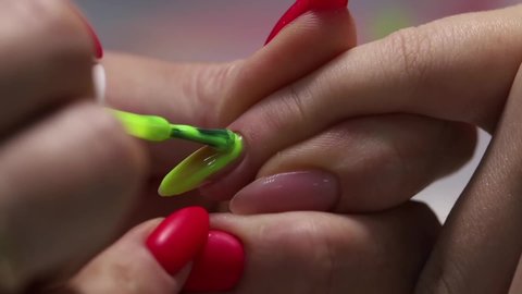 Professional manicure. Nail extension. Applying the main green color of the nail Polish to the prepared nail base. Procedure for creating long artificial gel nails in a modern beauty salon.