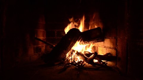 Romantic Fire in fireplace with logs and flames at home. Flames of burning wood logs in log cabin in mountains, close up. Burning woods in campfire at cold winter night. Barbecue. Red flames 