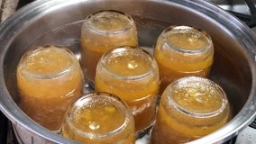 4K HD video of mason jars full of freshly made peach jam, upside down, boiling in a pot of water to process providing an average 2 year shelf life.
