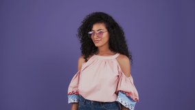 Afro-american lady in casual clothes. She enjoying video call on her smartphone, smiling, sending air kiss. Posing on purple background. Close up