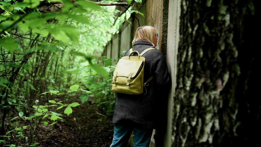 A girl explores an old concrete fence in the thicket. There