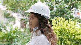 Portrait of female construction worker in medical mask and overalls on background of house under construction.4k slow motion video.