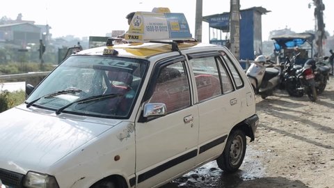 Delhi, India - 29 November 2019: A asian taxi driver washes his taxi car with a rag and pouring water from a canister near the city highway. Everyday life. Close-up