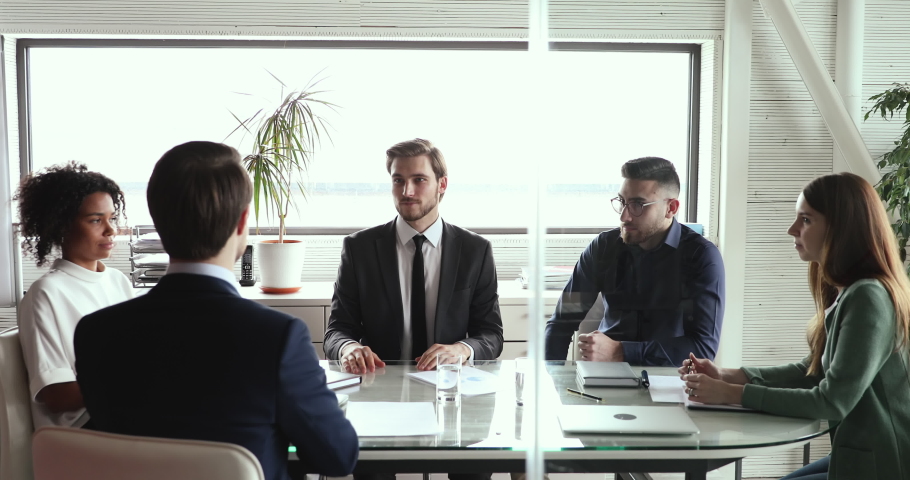 Two happy business partners wearing suits negotiate and handshake at multiethnic board group meeting table. Successful businessmen shake hands find teamwork business solution make partnership deal. Royalty-Free Stock Footage #1053818102
