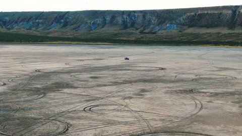 aerial survey of a group of tourists with a car at the bottom of a dry lake and the foot of a hill