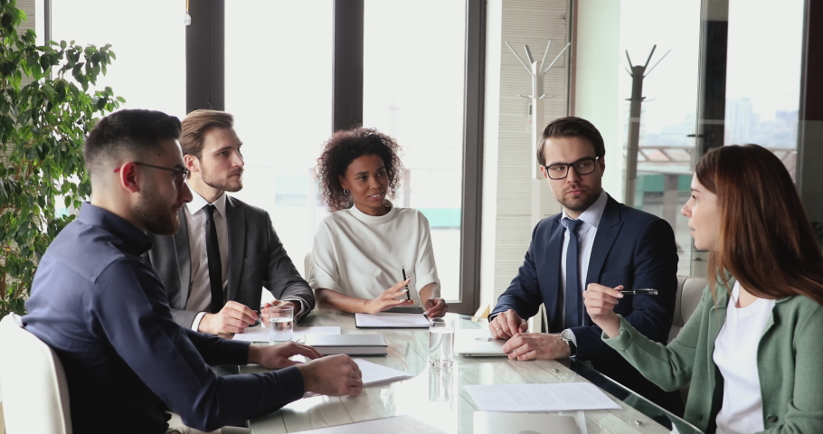 Female manager offering marketing idea at multiethnic group board meeting. Diverse business people team having teamwork discussion brainstorming in boardroom planning project sitting at office table. | Shutterstock HD Video #1053822287