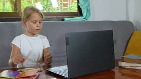 Cute child little girl counting numbers and does math homework online at home for elementary school. Distance education with children, online class and e-learning