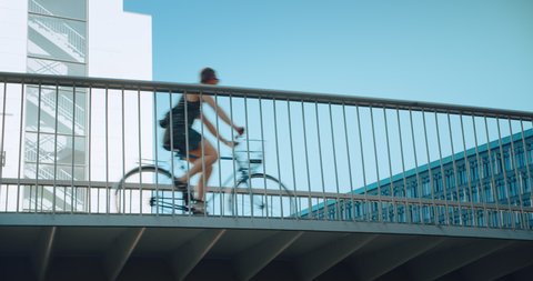 Female commuter goes to work or home on city bike. Cycling infrastructure of European city, elevated bike lane bridge in business district. Green and sustainable mobility solutions for traffic