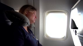 Closeup view video portrait of tired woman sleeping near window during flight by plane.