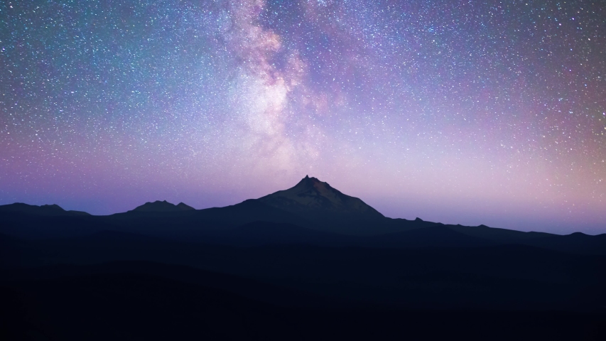 Time lapse of Milky Way over snowcapped mountain peak