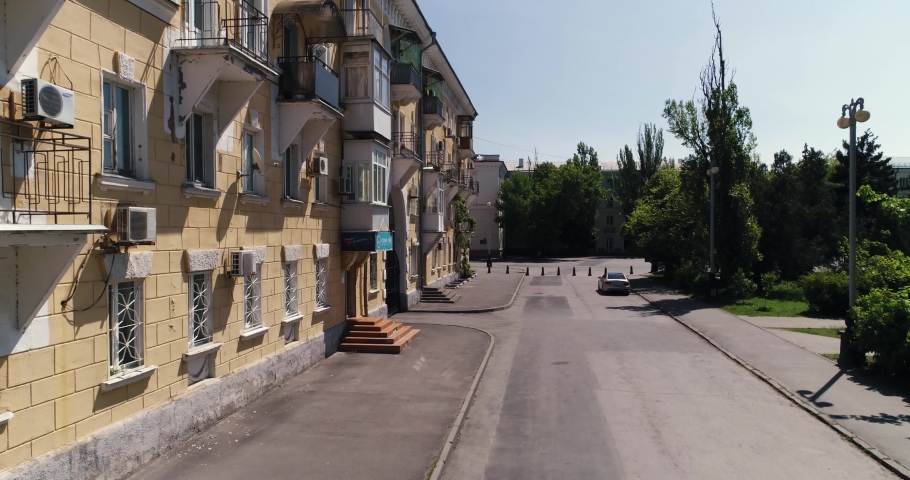 The historic city center. An old yellow house with balconies, windows and an arch stands in the middle of a square with trees