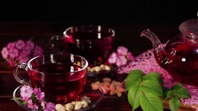 Pour tea from a teapot and drink from a glass mug. Red hot hibiscus tea in glass cup. Tea time: cup of tea, carcade, karkade, rooibos. Oriental, cozy, ceremony, tradition, japanese, leafy, hygge