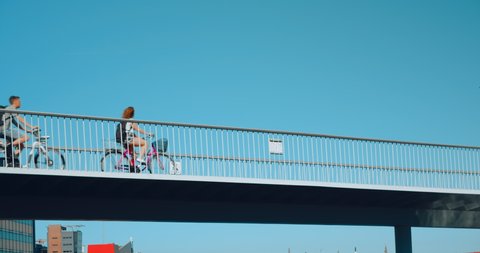 COPENHAGEN, DENMARK - JULY 2019. Bicycle commuters ride pedestrian and cycling traffic bridge in European city. Idyllic summer image of blue sky and happy cyclists enjoy safe infrastructure