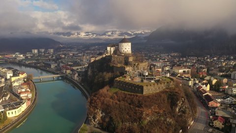 Aerial view of mountain town Kufstein with medieval hilltop fortress, dramatic winter scenery at sunrise, river Inn meandering through the valley - Austrian Alps from above, Tyrol, Austria, Europe