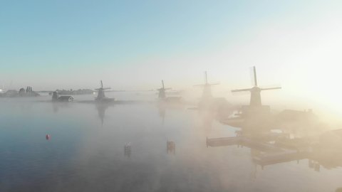 Drone flies over the windmills at the Zaanse Schans on a foggy morning one