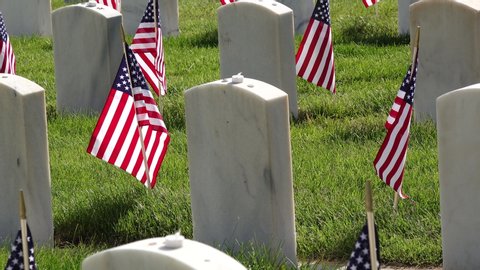 American Flags adorning military headstones at cemetery for Memorial Day