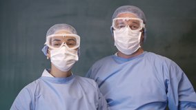 The male and female doctors are seriously looking at the camera. Slow motion 4K video.