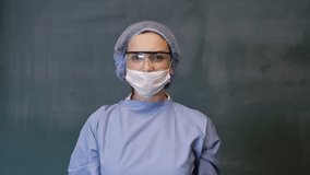 Female Doctor or Nurse Wearing Scrubs and Protective Mask and Goggles Banner. The doctor opens her mask. 4 K slow motion video.