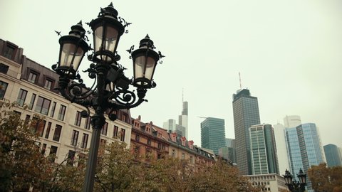 A combination of modern and old German Frankfurt am main architecture with tall skyscrapers in background old buildings, street lights in foreground, slide camera, rich forward, 4k, prores, slowmotion