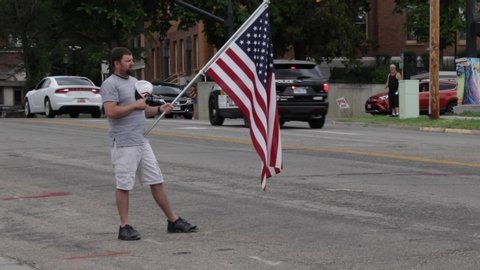 Ogden, Utah / United States - June 6 2020: Ogden City says goodbye to fallen heroic officer Nate Lyday as lone man holds an American flag as the procession drives past