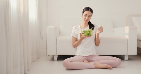 Young beautiful woman eating salad with attractive smile. Healthy eating concept.