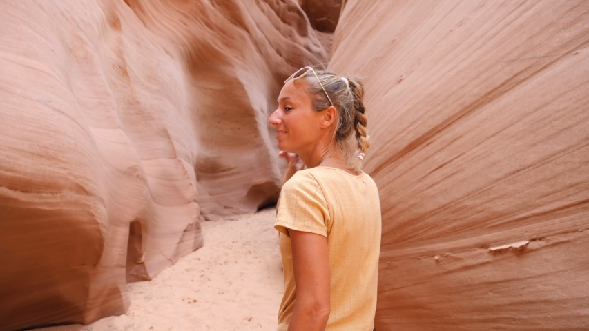 Young adventurous couple holding hands woman leading boyfriend walking into narrow canyon in the desert POV travel concept. Female waving hand, inviting partner to follow her  Royalty-Free Stock Footage #1053864050