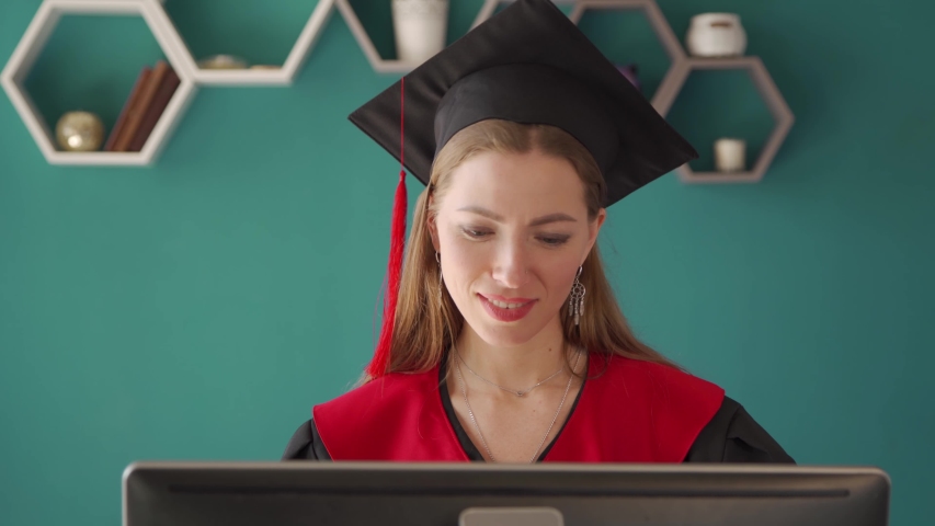 A happy adult student is sitting at a computer on a blue background. Online learning. Distance learning. Royalty-Free Stock Footage #1053872099