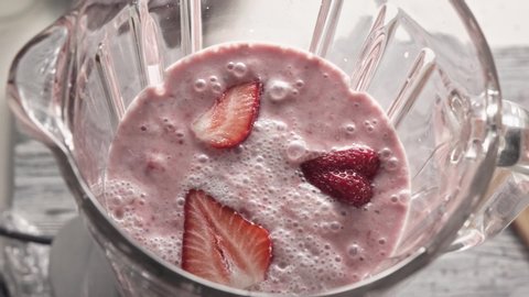 Sharp splash of cocktail from the bowl into table. Preparation of helathy organic milkshake, smoothies from strawberries, milk cream, chia seeds. Top view. Full HD video,240fps,1080p. Slow motion.