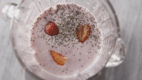 The female hand includes a mixer and a sharp splash of cocktail from the bowl. Preparation of a milkshake, smoothies from berries, cream, chia seeds. Top view. Full HD video,240fps,1080p. Slow motion.