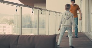 Father and son play in football on terrace of their apartment. Family spend free time. Weekend Holidays, Isolated concept. 4K video.
