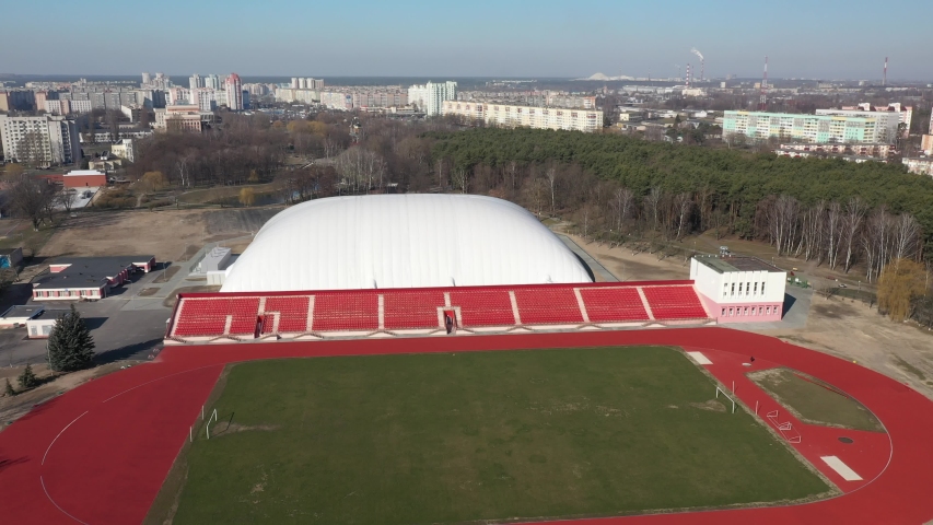 Top view of the football field. Grass on stadium in sunlight. Closeup of a green football field.  The view from the height. Green football field, red benches for spectators and fans.

